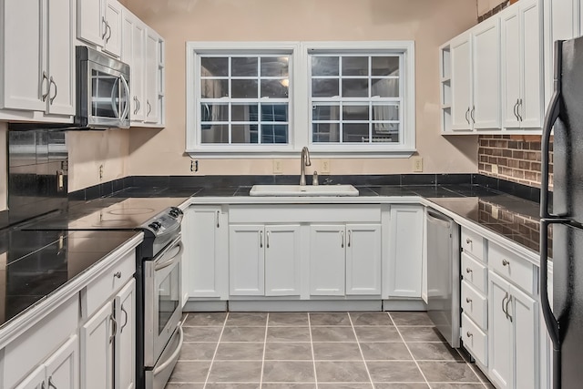 kitchen featuring sink, tasteful backsplash, light tile patterned flooring, white cabinets, and appliances with stainless steel finishes