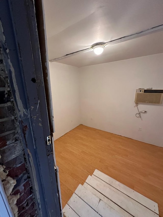 empty room with an AC wall unit and hardwood / wood-style flooring