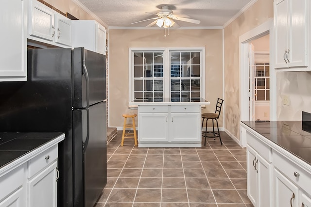 kitchen featuring white cabinets, tile countertops, black fridge, and ceiling fan