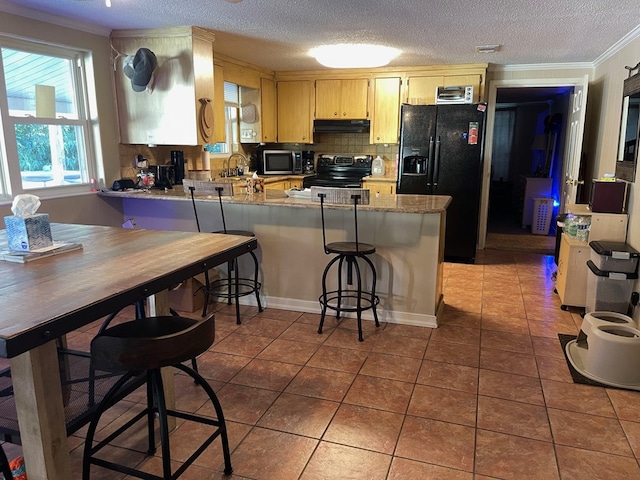 kitchen featuring tile patterned floors, kitchen peninsula, backsplash, black appliances, and ornamental molding