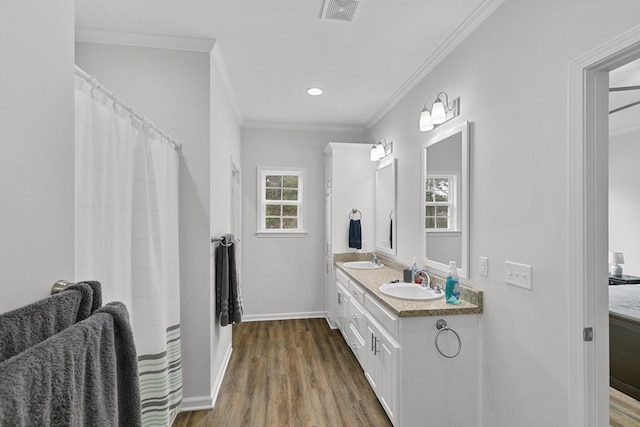 bathroom with a sink, ornamental molding, wood finished floors, and visible vents