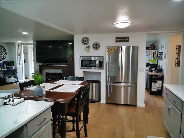 4301 County Road 156, Enterprise, AL 36330 - kitchen featuring appliances with stainless steel finishes, light wood-type flooring, gray cabinetry, a fireplace, and light stone counters
