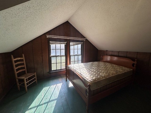 bedroom featuring wooden walls, a textured ceiling, dark hardwood / wood-style floors, and lofted ceiling