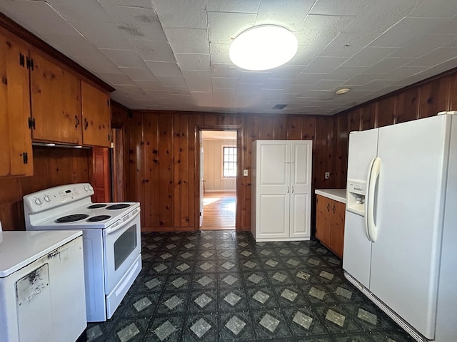 kitchen with washer / clothes dryer, wood walls, and white appliances