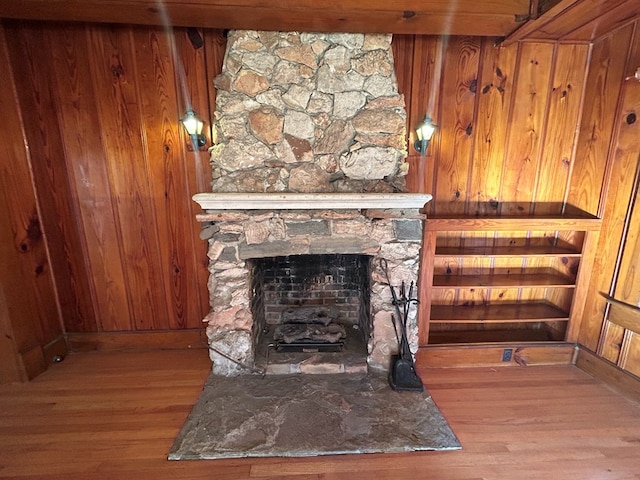 room details with a stone fireplace, wood walls, and hardwood / wood-style floors