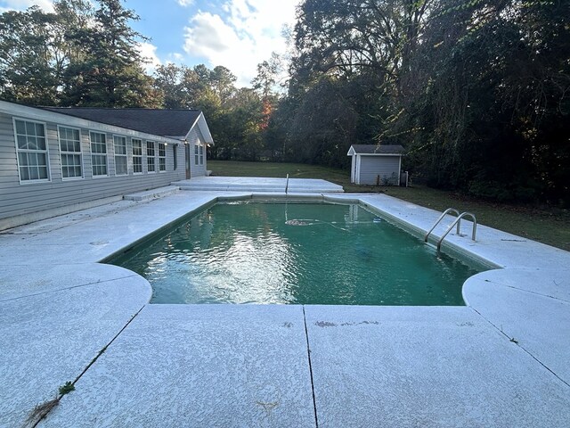 view of swimming pool with a storage shed and a patio