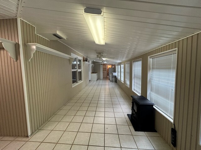 corridor featuring light tile patterned floors and wooden walls