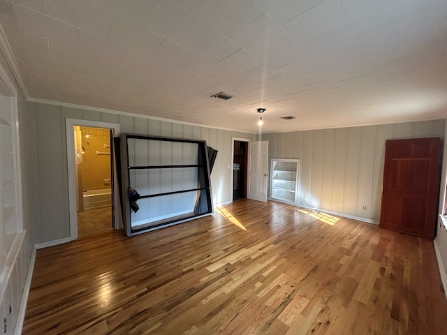 unfurnished bedroom with ensuite bathroom, wood-type flooring, and ornamental molding