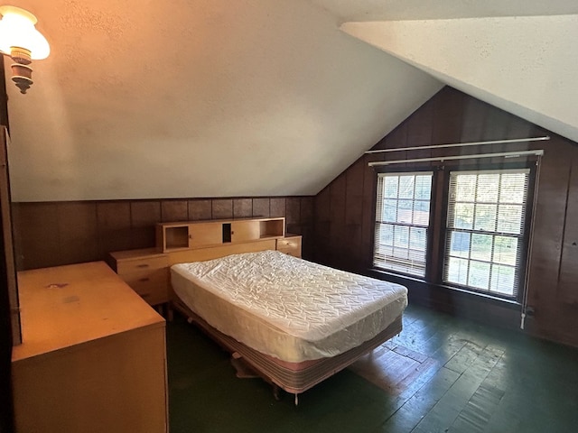 bedroom featuring dark hardwood / wood-style floors, lofted ceiling, a textured ceiling, and wooden walls