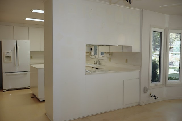 kitchen with white refrigerator with ice dispenser, white cabinets, and sink