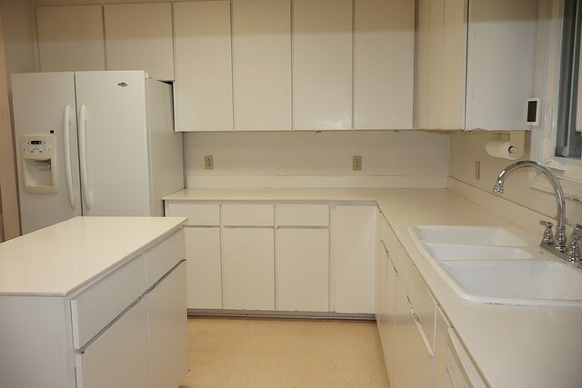 kitchen featuring white fridge with ice dispenser, white cabinets, and sink