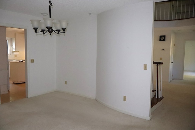 spare room with carpet flooring, a textured ceiling, and an inviting chandelier