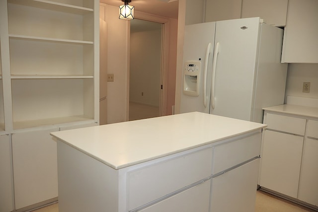 kitchen with a center island, white fridge with ice dispenser, and white cabinets