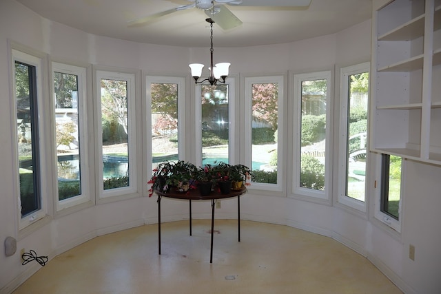 unfurnished sunroom with ceiling fan with notable chandelier