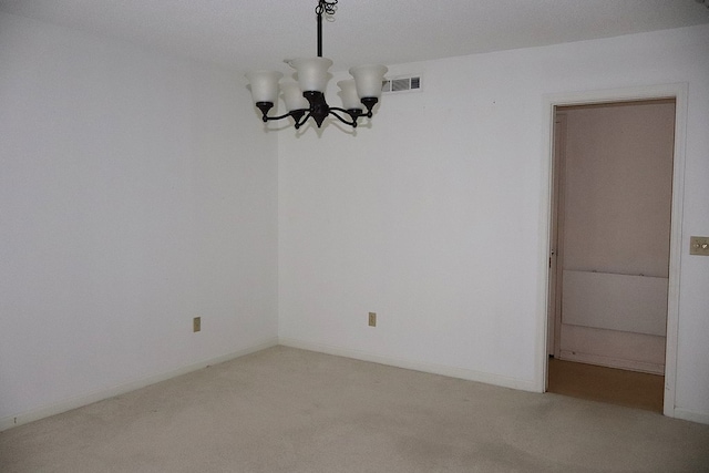 carpeted spare room with a textured ceiling and a chandelier