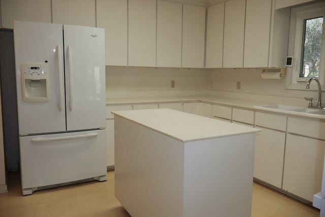 kitchen featuring a kitchen island, white fridge with ice dispenser, sink, and white cabinetry