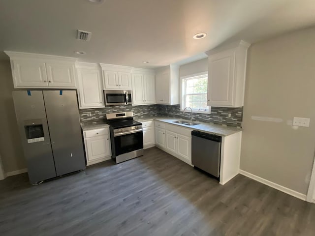 kitchen featuring white cabinets, sink, decorative backsplash, appliances with stainless steel finishes, and dark hardwood / wood-style flooring