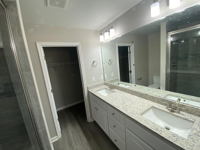 bathroom with a shower with door, vanity, wood-type flooring, and toilet