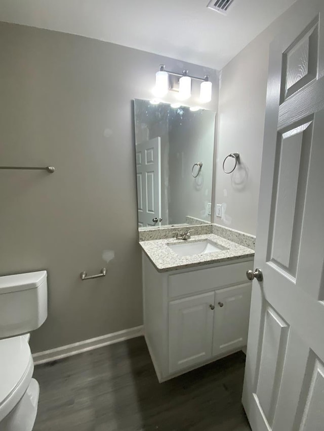 bathroom featuring wood-type flooring, vanity, and toilet