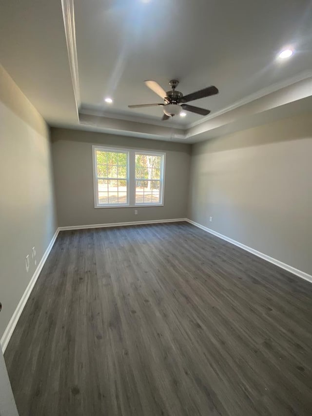 unfurnished room with a raised ceiling, ceiling fan, dark hardwood / wood-style floors, and ornamental molding