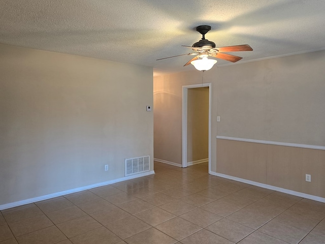 empty room with visible vents, light tile patterned flooring, ceiling fan, a textured ceiling, and baseboards