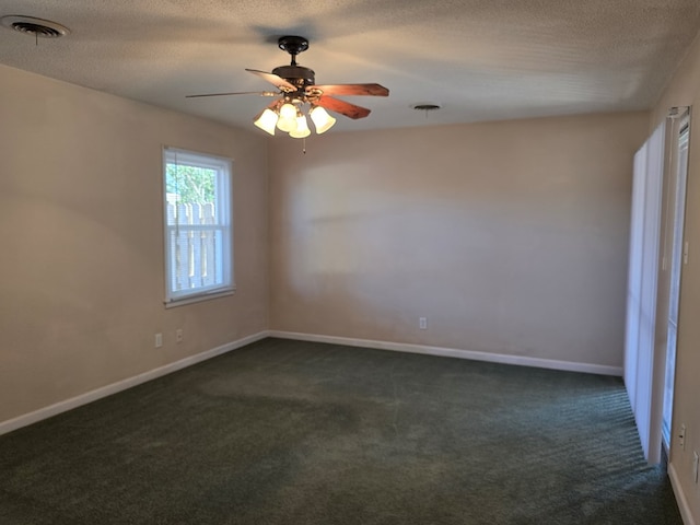 spare room with baseboards, visible vents, dark carpet, and a textured ceiling