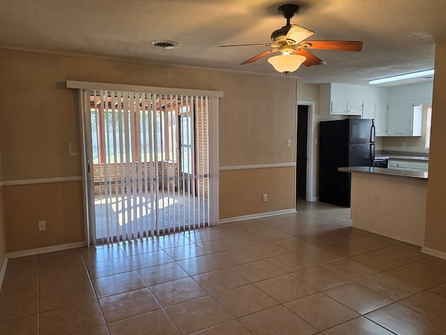 kitchen featuring light tile patterned floors, a ceiling fan, freestanding refrigerator, a textured ceiling, and white cabinetry