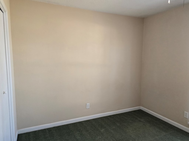 empty room with baseboards and dark colored carpet