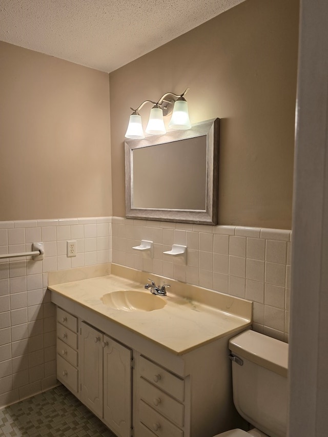 half bathroom with toilet, tile walls, a textured ceiling, and vanity