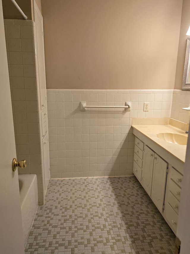 full bathroom with tile walls, a wainscoted wall, shower / bath combination, and vanity