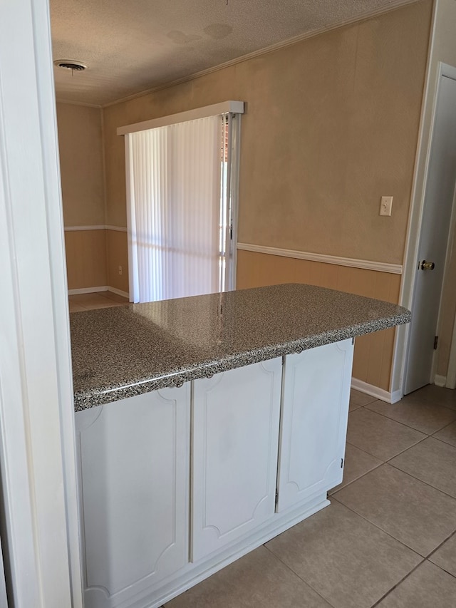 kitchen featuring ornamental molding, a textured ceiling, a peninsula, and light tile patterned floors