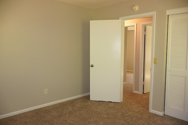 unfurnished bedroom featuring carpet floors, a textured ceiling, and a closet