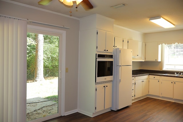 kitchen featuring ornamental molding, dark wood-type flooring, white cabinets, white fridge, and oven