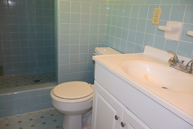 bathroom with tile patterned floors, walk in shower, vanity, tile walls, and toilet