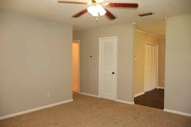 carpeted empty room with ceiling fan, crown molding, and a textured ceiling