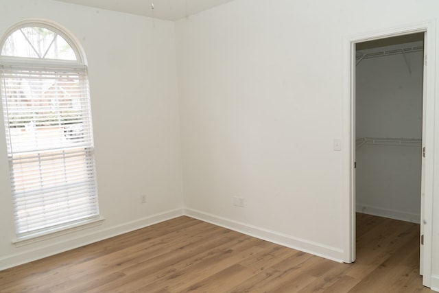 unfurnished bedroom with a spacious closet, light hardwood / wood-style floors, and a closet