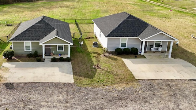 view of front of house with central air condition unit, fence, concrete driveway, and a front yard