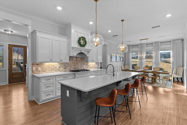 kitchen featuring pendant lighting, stainless steel gas stovetop, white cabinets, tasteful backsplash, and a large island