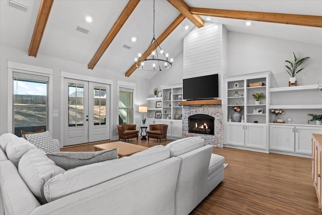 living room featuring french doors, high vaulted ceiling, a chandelier, wood-type flooring, and a fireplace