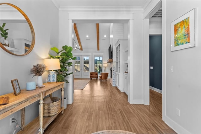 hallway with beam ceiling, light wood-type flooring, and french doors