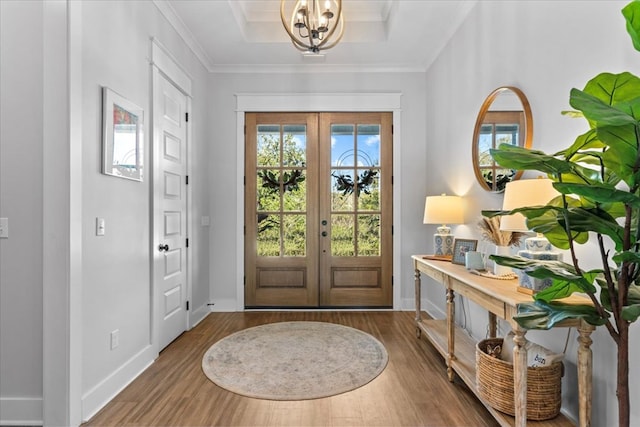 entrance foyer featuring french doors, a raised ceiling, crown molding, and wood-type flooring