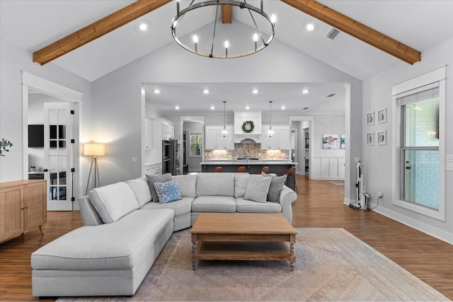 living room featuring plenty of natural light, beam ceiling, and a chandelier