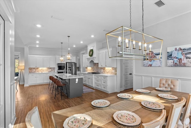 dining area with an inviting chandelier, dark wood-type flooring, and ornamental molding