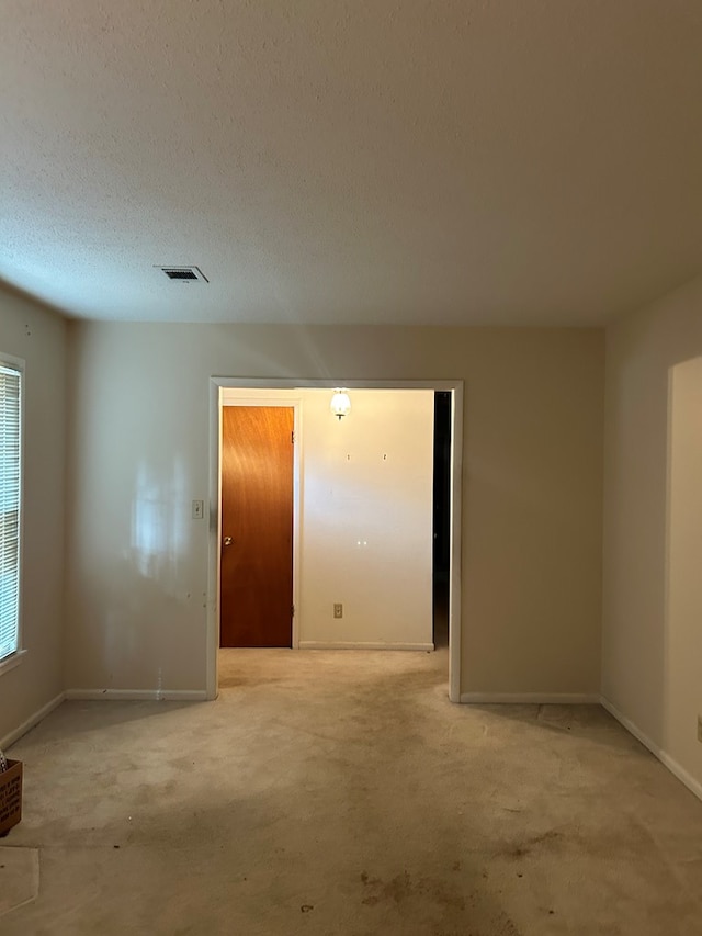 carpeted spare room featuring a textured ceiling