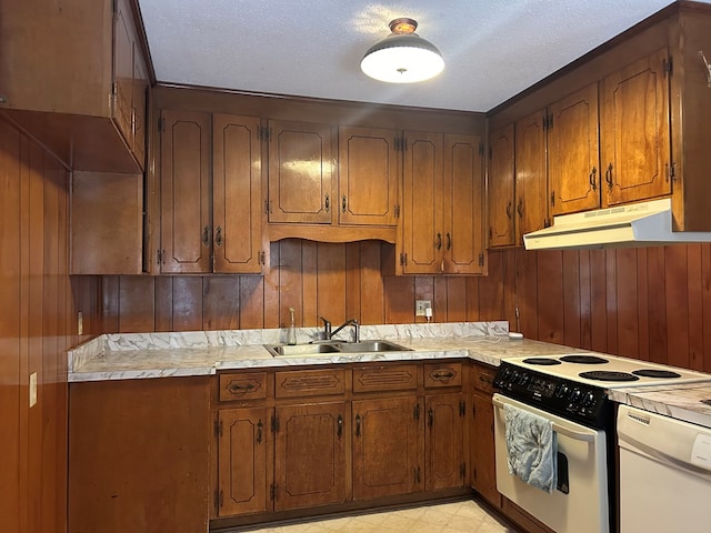 kitchen with a textured ceiling, wooden walls, sink, and white appliances