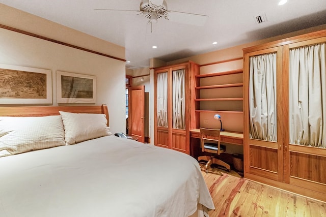 bedroom with ceiling fan, built in desk, and light hardwood / wood-style floors