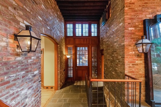 foyer entrance featuring a towering ceiling and brick wall