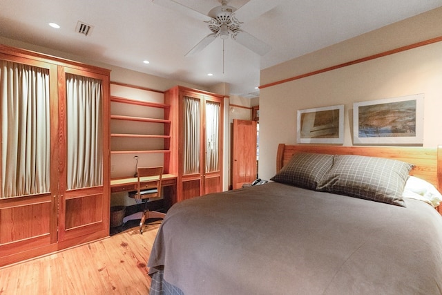 bedroom featuring ceiling fan, light hardwood / wood-style floors, and built in desk