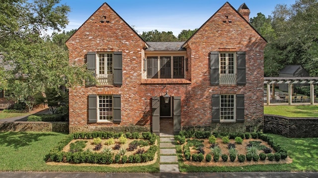 english style home with a pergola and a front yard