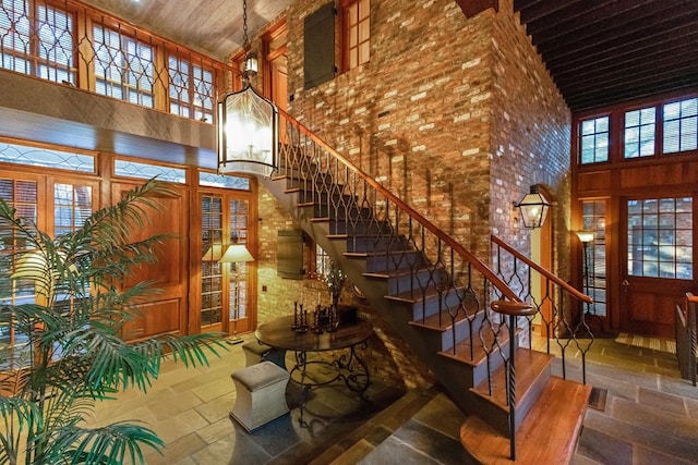 stairway with a towering ceiling, an inviting chandelier, and wooden ceiling